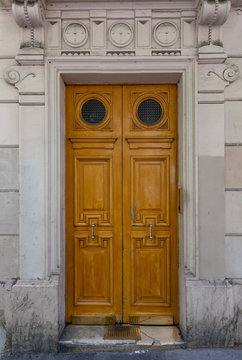 Old wooden door. Elegant old double door entrance of building in Paris France. Vintage wooden doorway and stucco fretwork wall of ancient stone house with round medallions. Ornate carving wood door.
