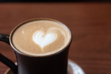 Coffee cup with latte art foam on wood table in coffee shop with copy space.Coffee is one of the most popular beverages.Improve Energy Levels and Burn Fat