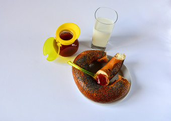 Fresh donated crispy bagel with poppy seeds on a white plate with tasty natural apricot jam and a...