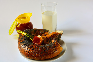 Fresh donated crispy bagel with poppy seeds on a white plate with tasty natural apricot jam and a...