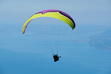 Paraglider flying over the Garda Lake (Lago di Garda or Lago Benaco), Panorama of the gorgeous Garda lake surrounded by mountains. Paragliding is very popular sport in Monte Baldo. Malcesine, Italy