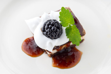 waffle cake with blackberry and whipped cream with mint leaf on white plate
