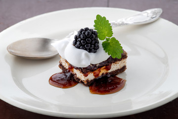 waffle cake with blackberry and whipped cream with mint leaf on white plate and spoon on it