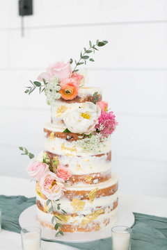 Naked Wedding Cake Decorated with Gold Foil and Flowers, Three Tiered Cake, White Background, Copy Space