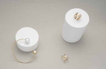 Golden pearl bracelet with golden rings on white cylinders