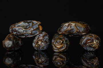 Group of six whole dried brown date medjool isolated on black glass