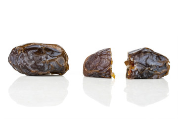 Group of one whole two halves of dried brown date medjool isolated on white background