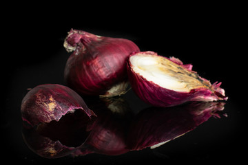 Group of one whole one half one piece of stale red onion isolated on black glass