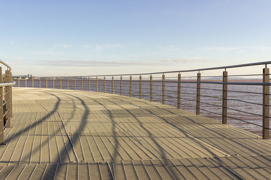 A horizontal picture of a iron bridge over the sea. Perspective and vanishing point. Intense blue sky. Porto Alegre, Brazil. 2019