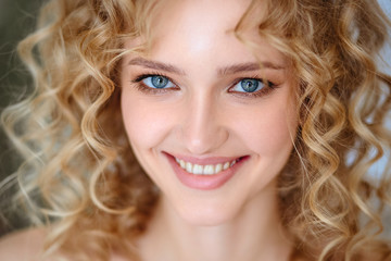 Close up portrait of blonde charming young woman with curly hair and natural makeup. Sunny morning, spa and care