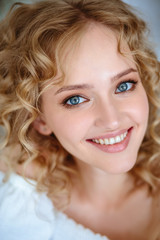 Close up portrait of blonde charming young woman with curly hair and natural makeup. Sunny morning, spa and care