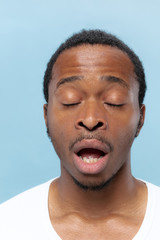 Obraz premium Close up portrait of young african-american man in white shirt on blue background. Human emotions, facial expression, ad, sales concept. A few seconds before the sneezing.
