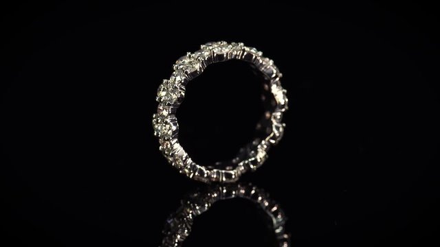 Beautiful wedding ring rotating on dark background. White gold ring with diamonds