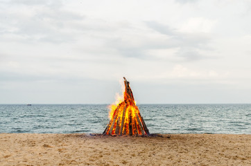 Big bonfire by the sea. Bonfire on the sand. Summer evening with a fire.