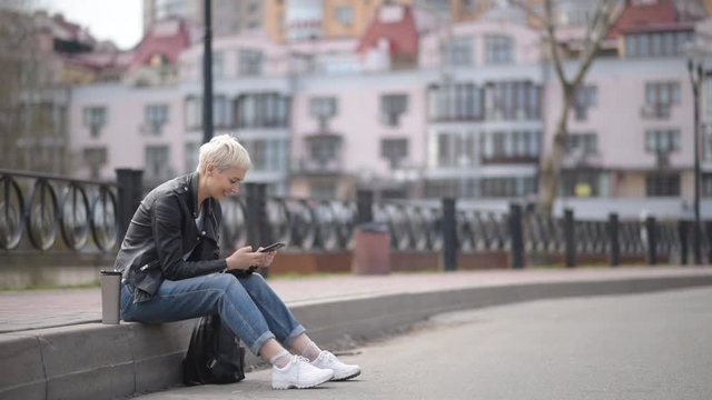 girl sitting on the street, smiling and wright on the phone
