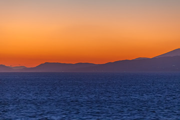 Dreamlike sunset with orange sky with Aegean Sea islands background