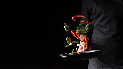 The chef prepares the vegetables in a skillet frying them. Hotel business and the menu in restaurants, the book of recipes. On a black background banner