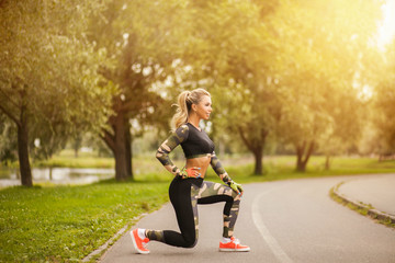 Beautiful healthy fitness blond woman in fashion sport wear running and practices yoga in the park at sunset