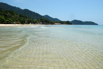 View on the clean transparent sea on a background of coastline with beach, mountains and blue sky. Koh Chang, Thailand.