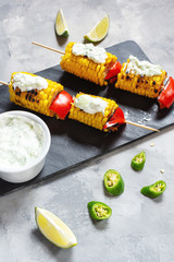 Grilled sweet corn on the sticks, concrete table