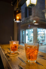 Closeup glass of spritz aperol cocktail decorated with orange at bright bar counter background.