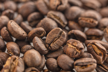 Many coffee grains. Part of the foreground and background in blur. Top view at an angle. For design.