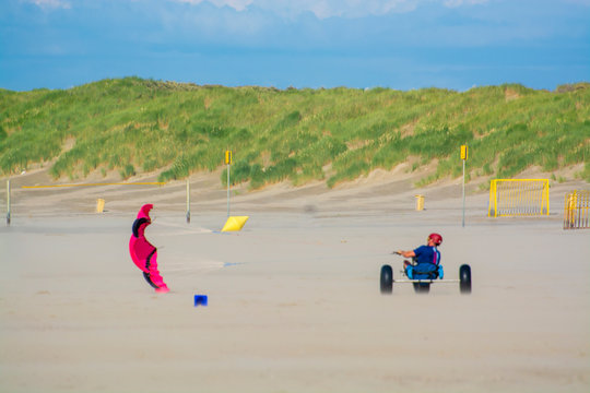 Off-road driving wind buggy on sandy beach with green sandy dunes