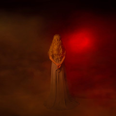 A mysterious woman blonde in a long gray dress goes to the gates of hell. The background is a fog...