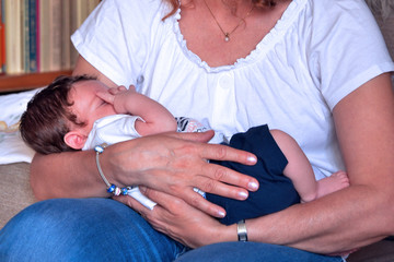 una donna tiene affettuosamente in braccio un neonato che dorme - 281501269