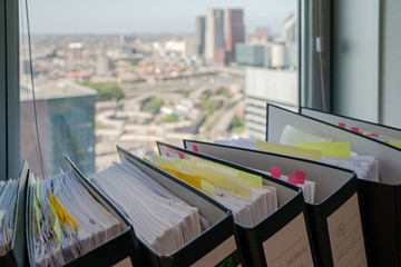 Binders with documents at a window of an office on the 23rd floor in The Hague. The city skyline can be seen through the window.