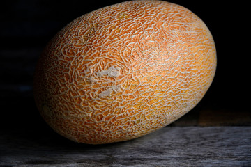Whole fruit of a melon with a knife on an old rustic table.