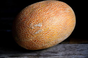 Whole fruit of a melon with a knife on an old rustic table.