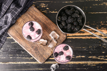 Glasses of tasty blackberry lemonade on dark wooden table