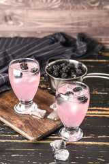 Glasses of tasty blackberry lemonade on dark wooden table