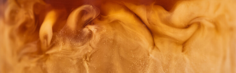 close up view of brown coffee mixing with white milk in glass, panoramic shot
