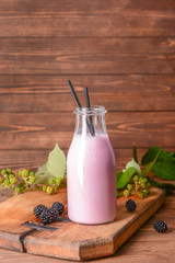 Bottle of tasty blackberry smoothie on wooden table