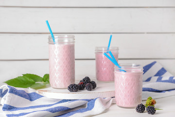 Jars of tasty blackberry smoothie on table