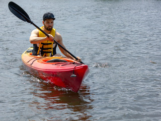 man in red kayak on a river in summer