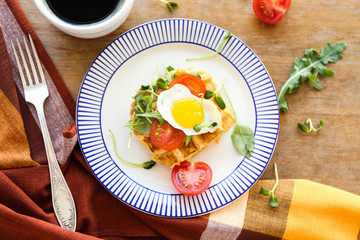 Plate with tasty waffles and fried egg on wooden table