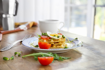 Plate with tasty waffles and fried egg on wooden table