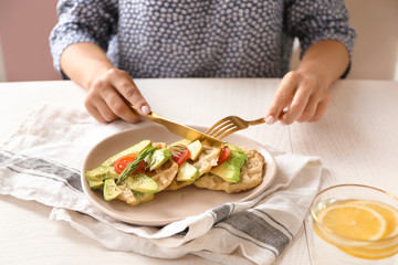Woman eating tasty waffles at table