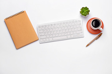 Modern computer keyboard with stationery and cup of coffee on white background