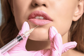 Young woman receiving injection of filler in lips, closeup