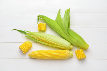 Fresh corn cobs on white wooden background