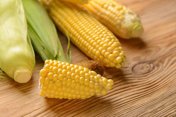 Fresh corn cobs on wooden background