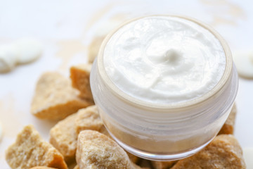Jar of natural cream and lump brown sugar on table, closeup