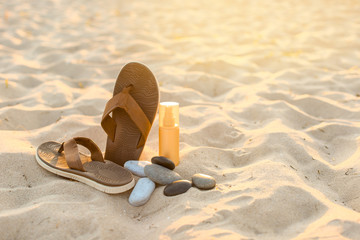 Flip-flops with pebbles and cosmetics on sand beach