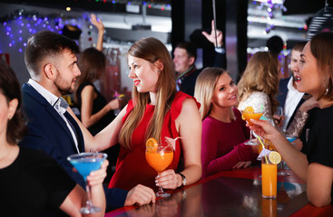 Woman and her boyfriend with cocktails having fun at nightclub