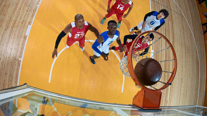 Professional basketball player in action performing slam dunk in a basketball hoop on a sports arena. View from above the hoop.