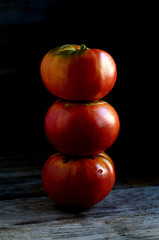 Ripe red tomatoes stacked in an orderly manner on an old rustic table.